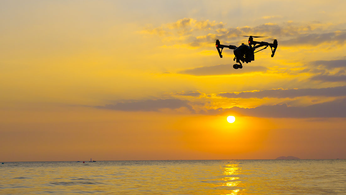Geospatial-banner-drone-over-the-sea-sunset-1102x620px Drone flying over the sea at sunset
